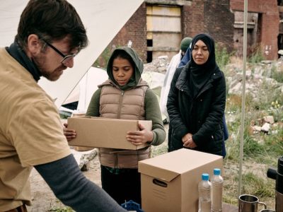 young-bearded-social-employee-glasses-giving-food-water-black-refugee-girl-with-open-box-outdoors_274679-28171